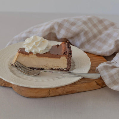 slice of peanut butter cheesecake with chocolate ganache and whipped cream